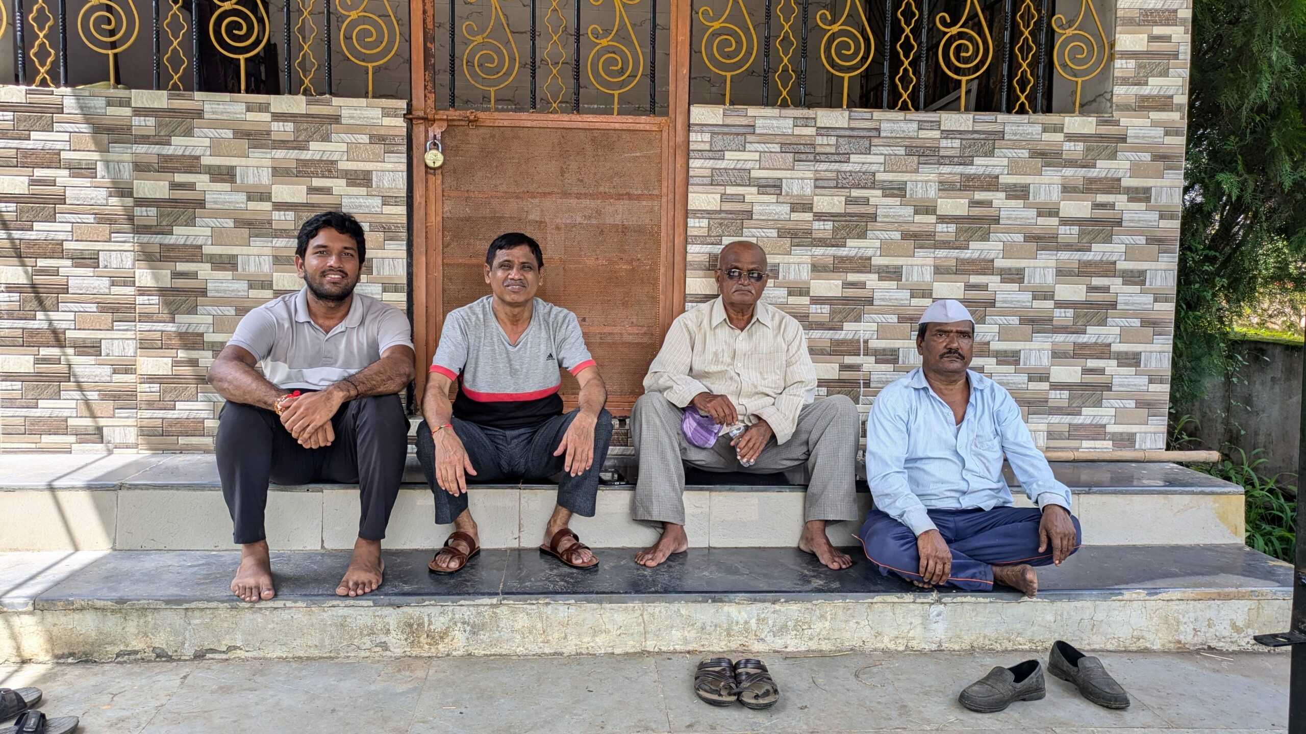 Rohan sits with three men on stairs outside a locked door.