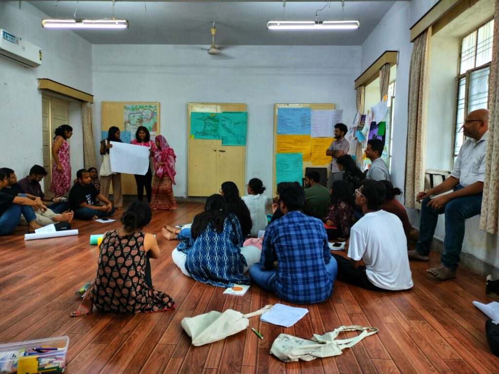 A picture of our classroom with fellows sitting on the ground and looking ahead.