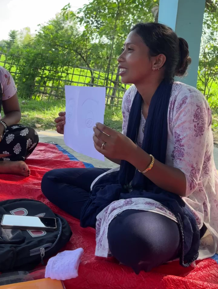 Santona holding a paper with a middle crease explaining how the participants can draw in their halves and also collaborate simultaneously