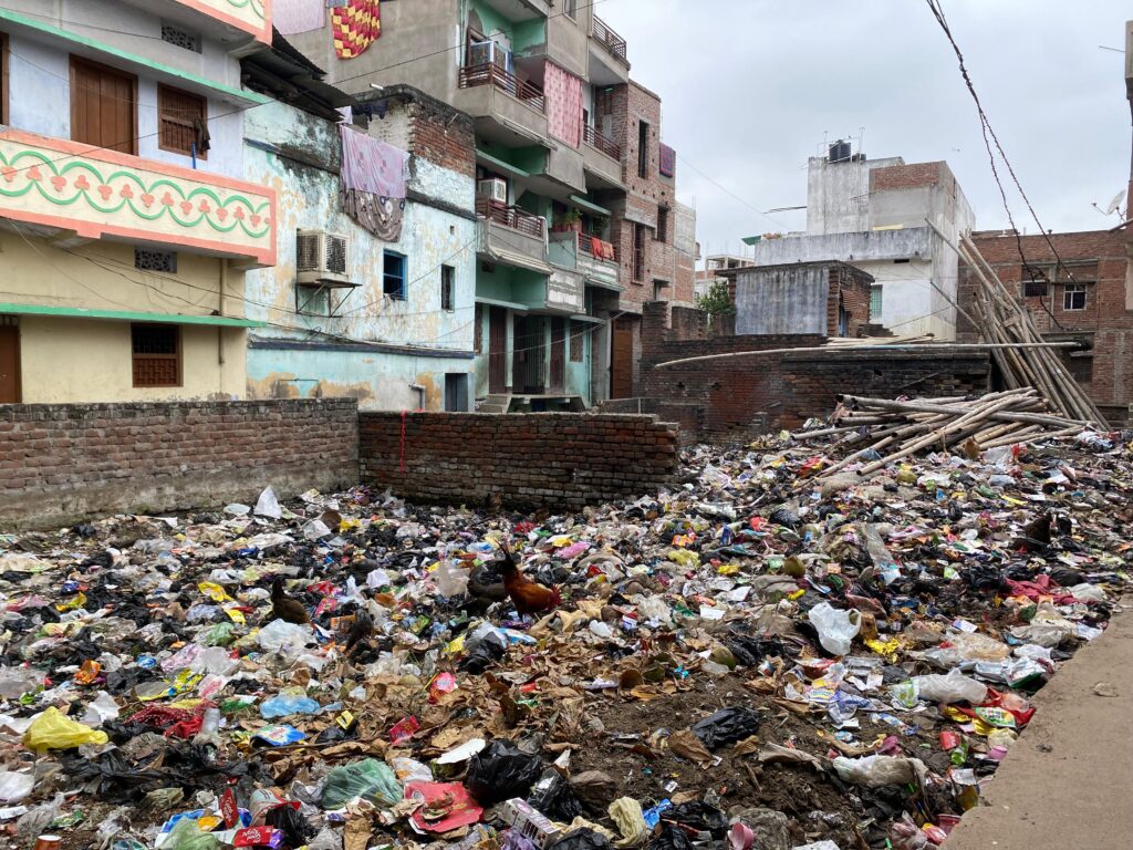 A closeup picture of an urban slum, with a lot of garbage spill against some houses.