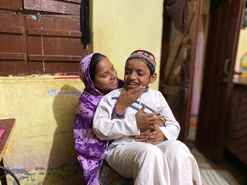 A woman is sitting and holding a child's face towards her, they're both laughing.