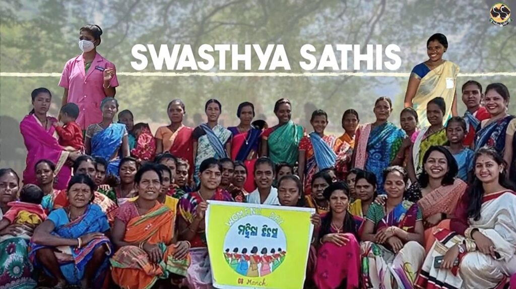 An image of several swasthya sathis sitting/ standing and smiling at the camera for a group photo.