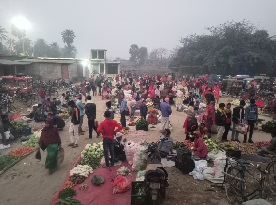 Scene from a market in Bihar. There are people all around and vegetable hawkers with their vegetables.